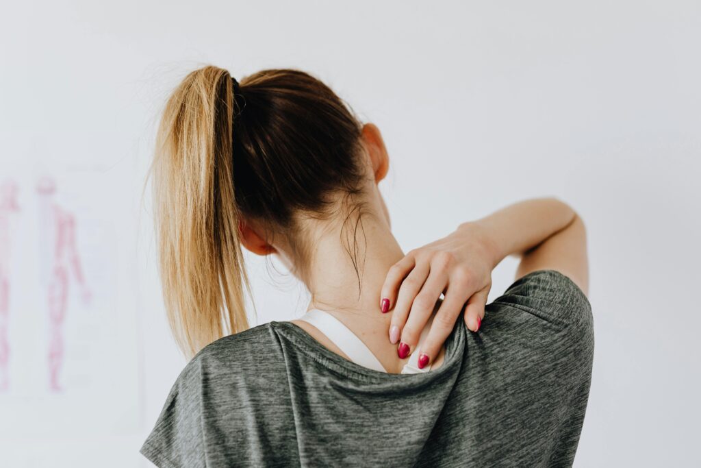 A woman in casual clothing holds her neck, indicating pain or discomfort. Hondro Sol