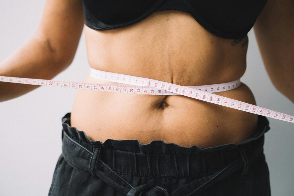 A person measuring their waist with a tape, symbolizing fitness and health goals. Matcha Slim
