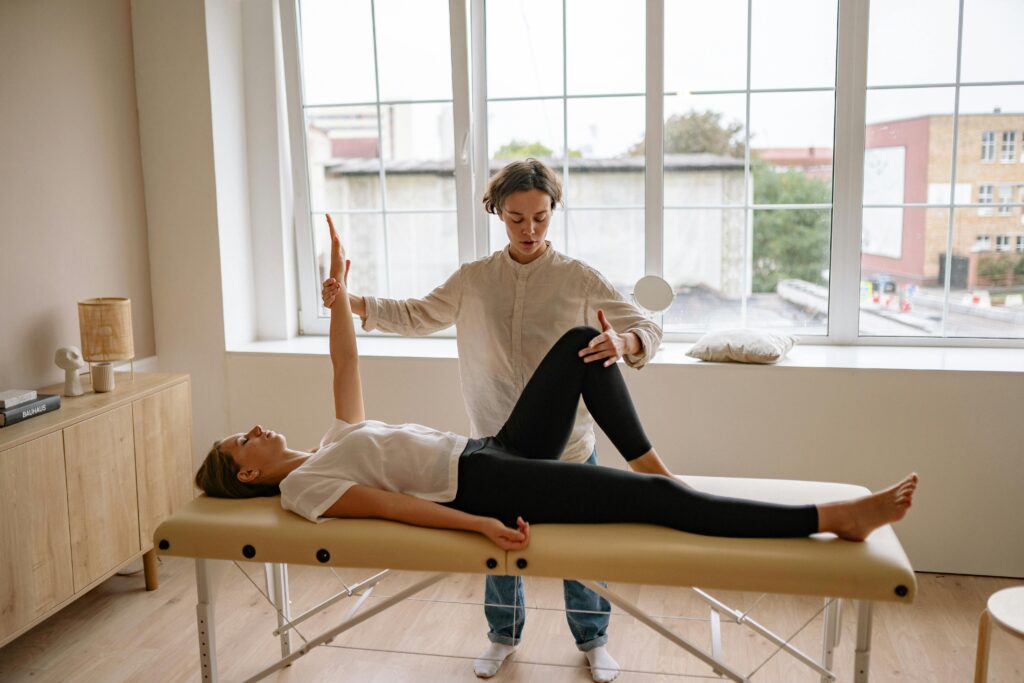 A specialist performs therapy on a woman lying on a massage table in a modern clinic setting. Hondro Sol
