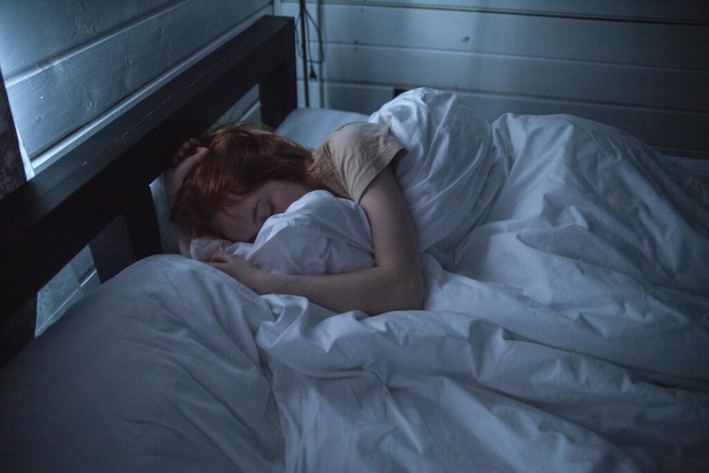 A woman sleeping peacefully in a cozy bedroom, enveloped by soft white sheets, under the gentle glow of night lighting.
Aeroflow