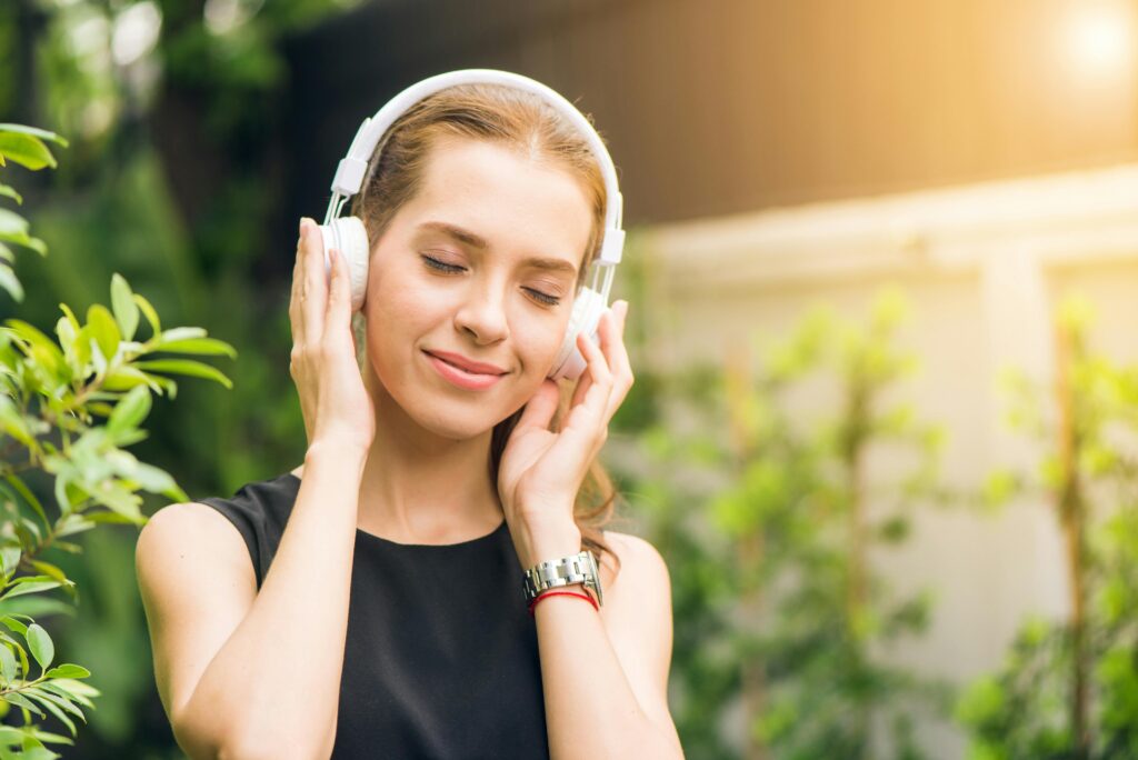 Smiling woman listening to music with headphones in sunny garden setting. top 7 best headphones on Amazon