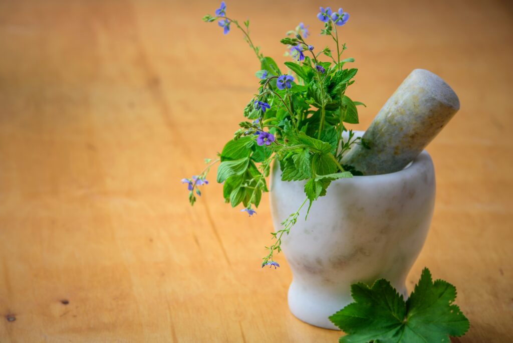 Marble mortar and pestle with fresh herbs and flowers on wooden table enhancing natural health and cooking aesthetics.Moringa Magic