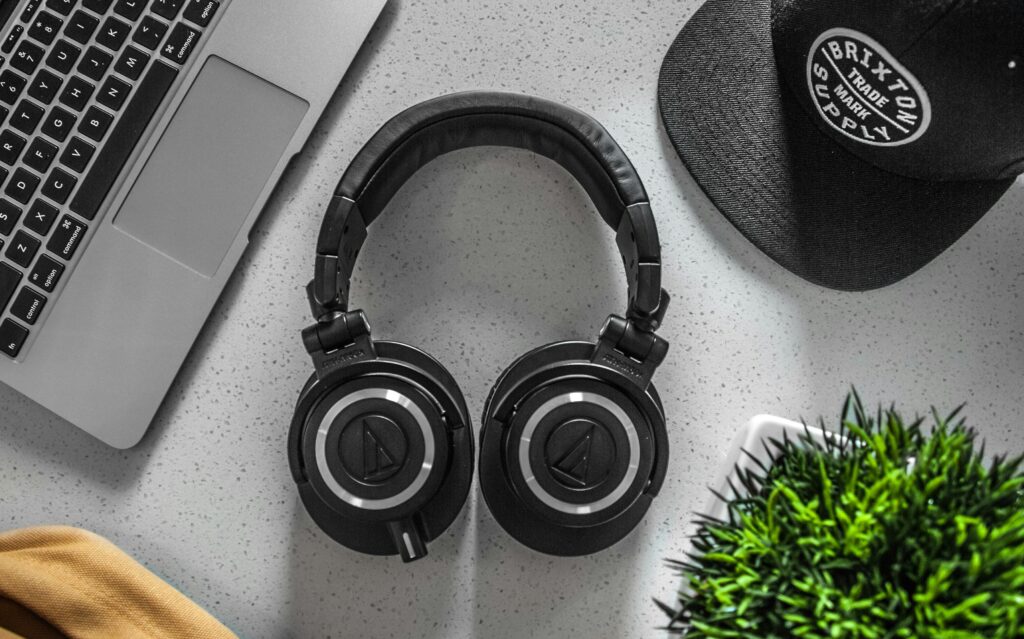 A stylish overhead shot of headphones with a laptop, cap, and decor on a desk. Top 7 Best Headphones on Amazon