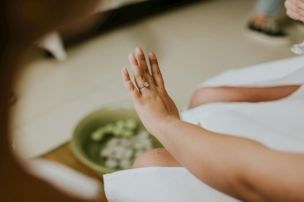 A close-up of a woman's hand adorned with a diamond engagement ring, captured indoors.enhance nail and skin NanoDefense Pro
